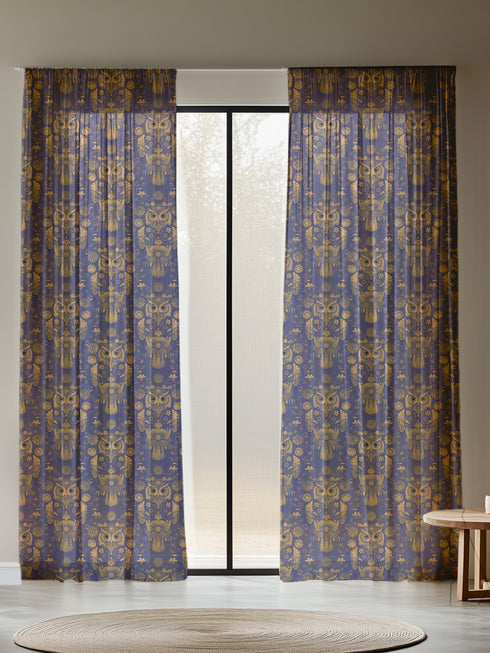 A sheer curtain panel featuring a repeating pattern of ornate golden owls surrounded by delicate floral designs and botanical elements on a deep navy background. The fabric has a fine linen-like texture with translucent qualities.